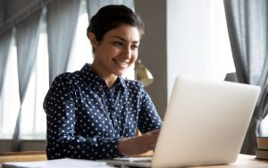 A smiling research administrator completes a survey on a laptop